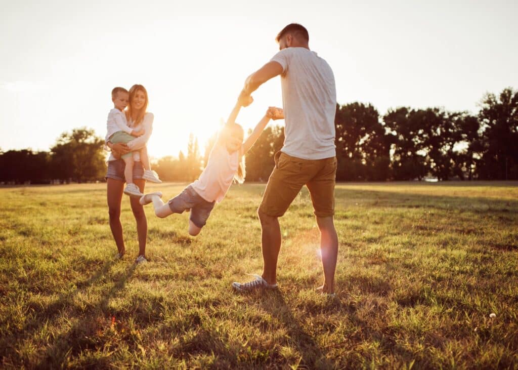 A family with two adults and two young children enjoying a moment together at sunset in the Roseburn community in Fort Saskatchewan, Alberta.