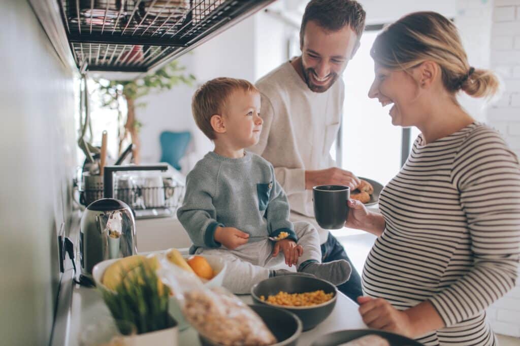 Two adults and a young child gathered in a kitchen preparing food, representing everyday family life in the Roseburn community in Fort Saskatchewan, Alberta.