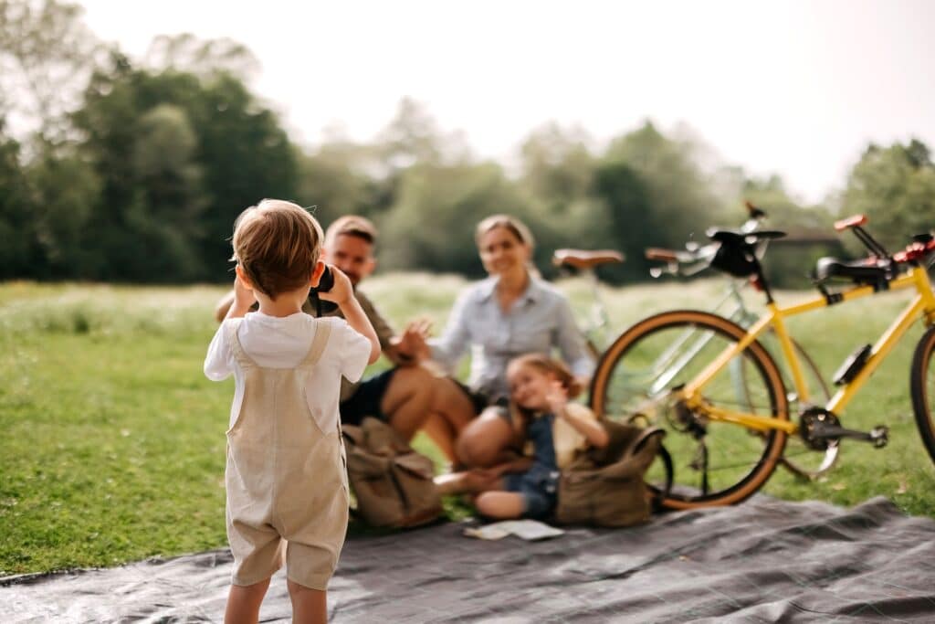 A family enjoying a picnic outdoors in the Roseburn community in Fort Saskatchewan, Alberta, as a young child takes their photo.