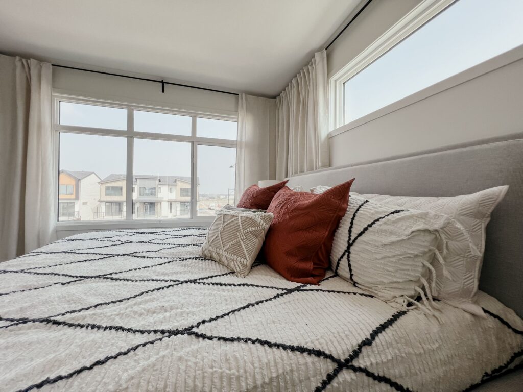Primary bedroom with large windows and modern finishes in a Cantiro townhome in Roseburn, Fort Saskatchewan, Alberta.