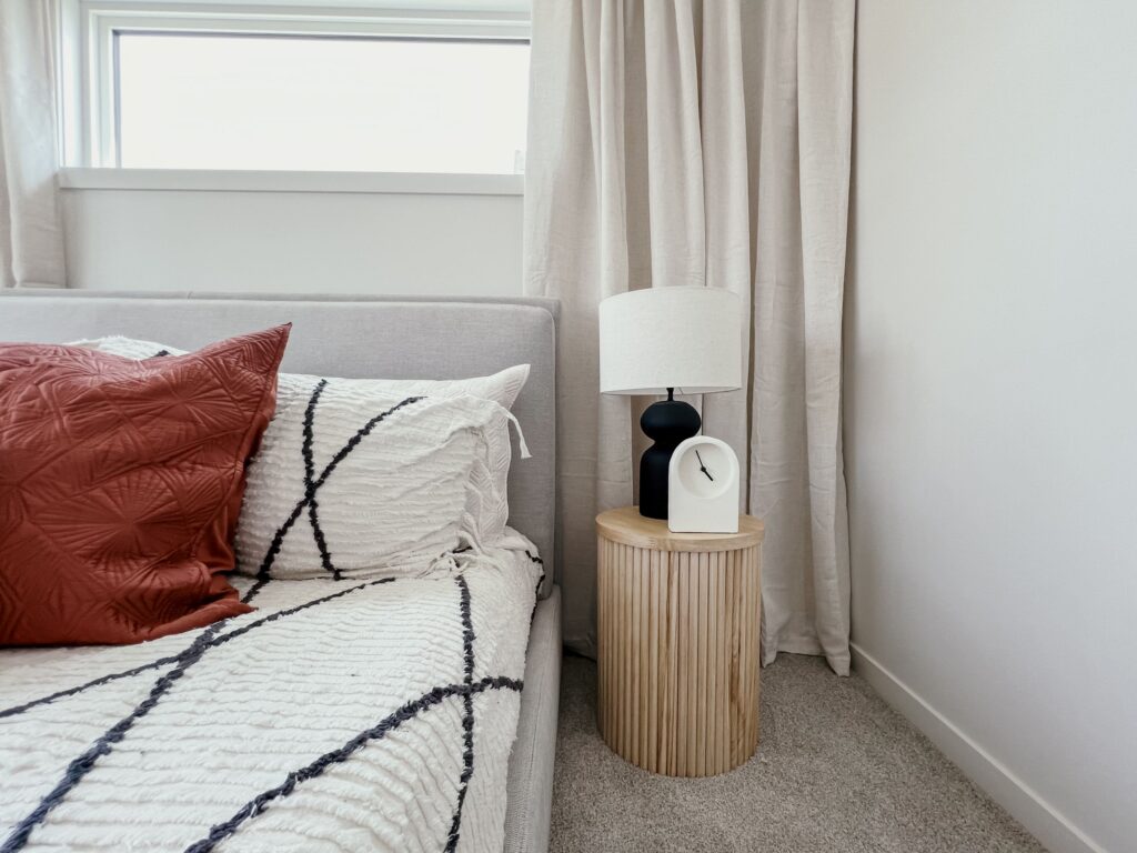 Bedroom detail featuring a bedside table, lamp, and layered textiles in a Cantiro townhome.