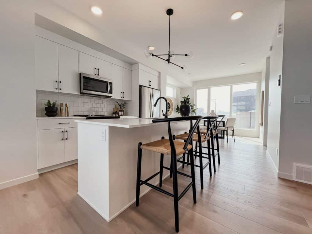 Open‑concept kitchen and dining area with island seating in a Cantiro townhome in Roseburn, Fort Saskatchewan, Alberta.