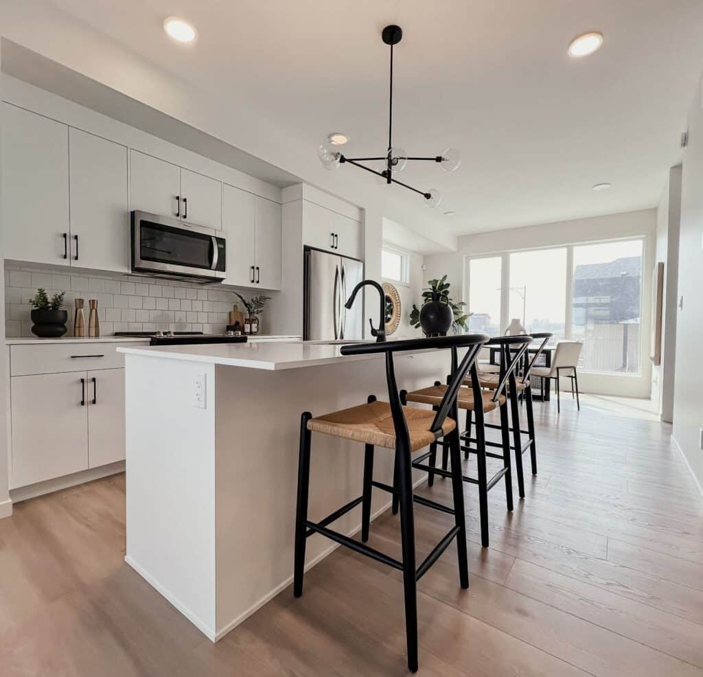 Open‑concept kitchen and dining area with island seating in a Cantiro townhome in Roseburn, Fort Saskatchewan, Alberta.