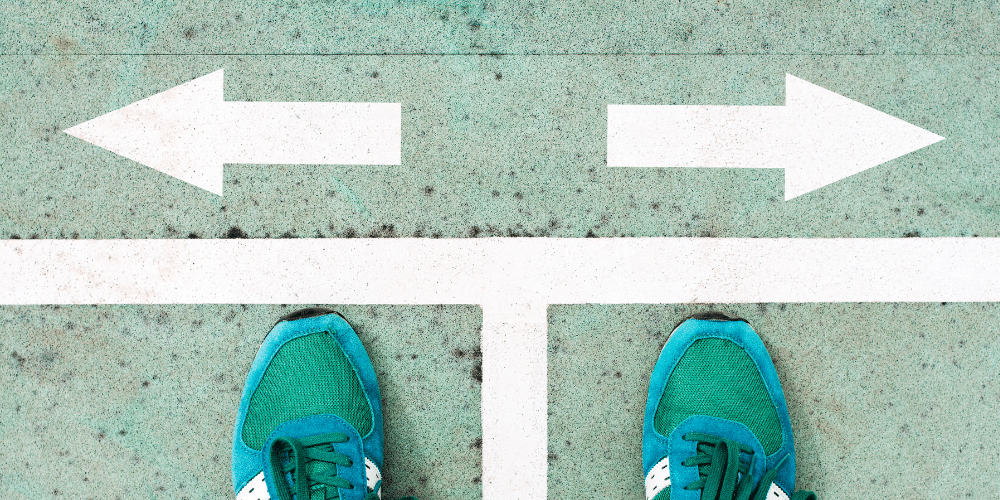 Person standing at a directional fork, illustrating how to choose between the best home builders in Edmonton and navigate home construction decisions in Edmonton.