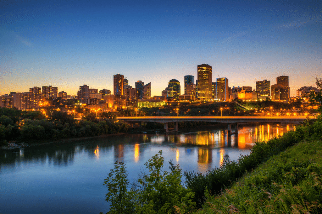 Downtown Edmonton skyline at dusk overlooking the North Saskatchewan River, showcasing one of the many lifestyle options available when comparing Edmonton communities.