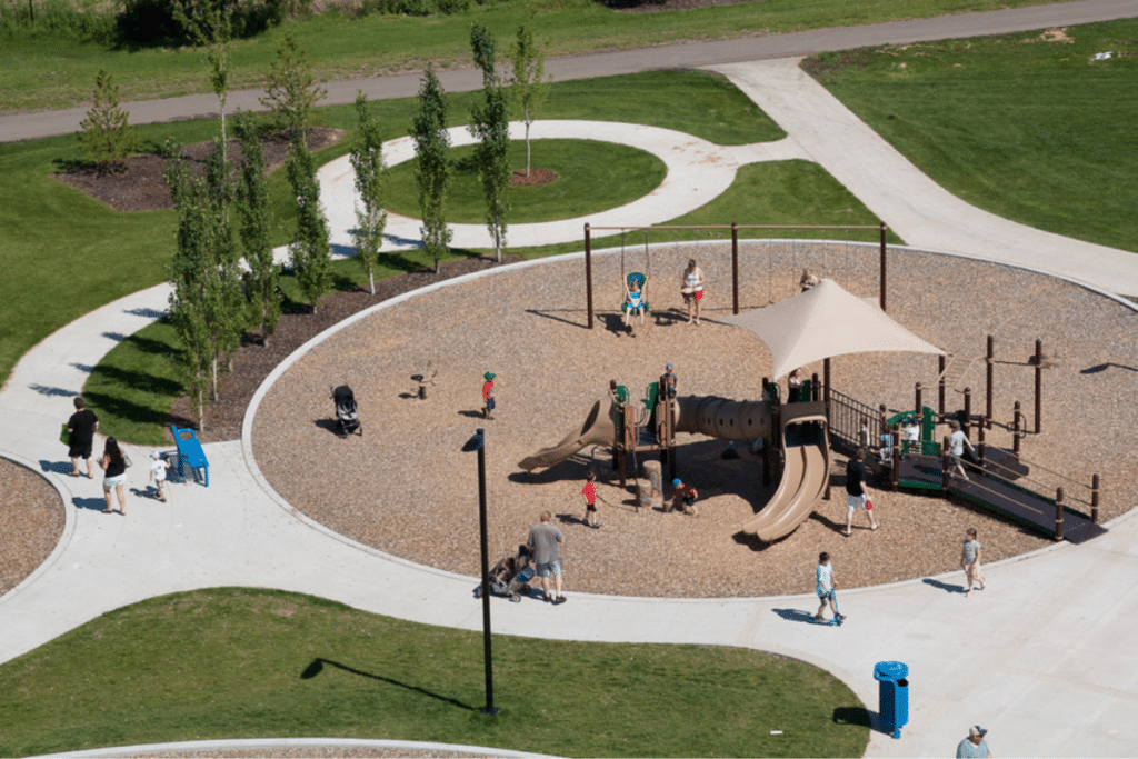 Families enjoying a community playground surrounded by walking paths and green space in a master-planned neighbourhood.